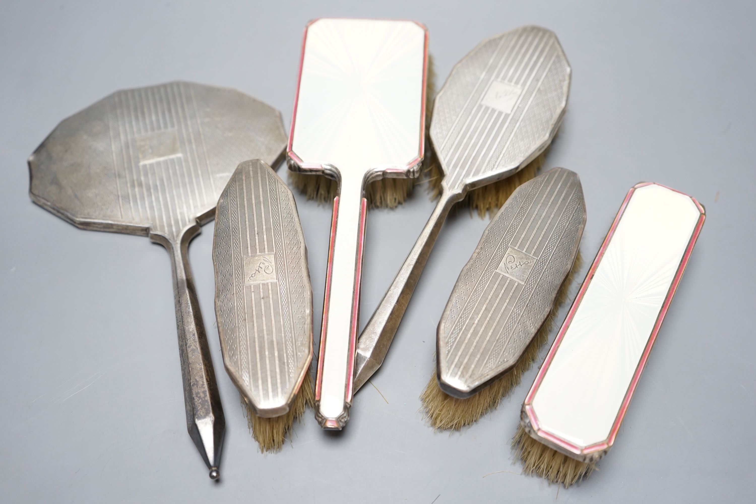 Two 1950's silver and enamel mounted brushes and an earlier four piece silver mounted brush set.